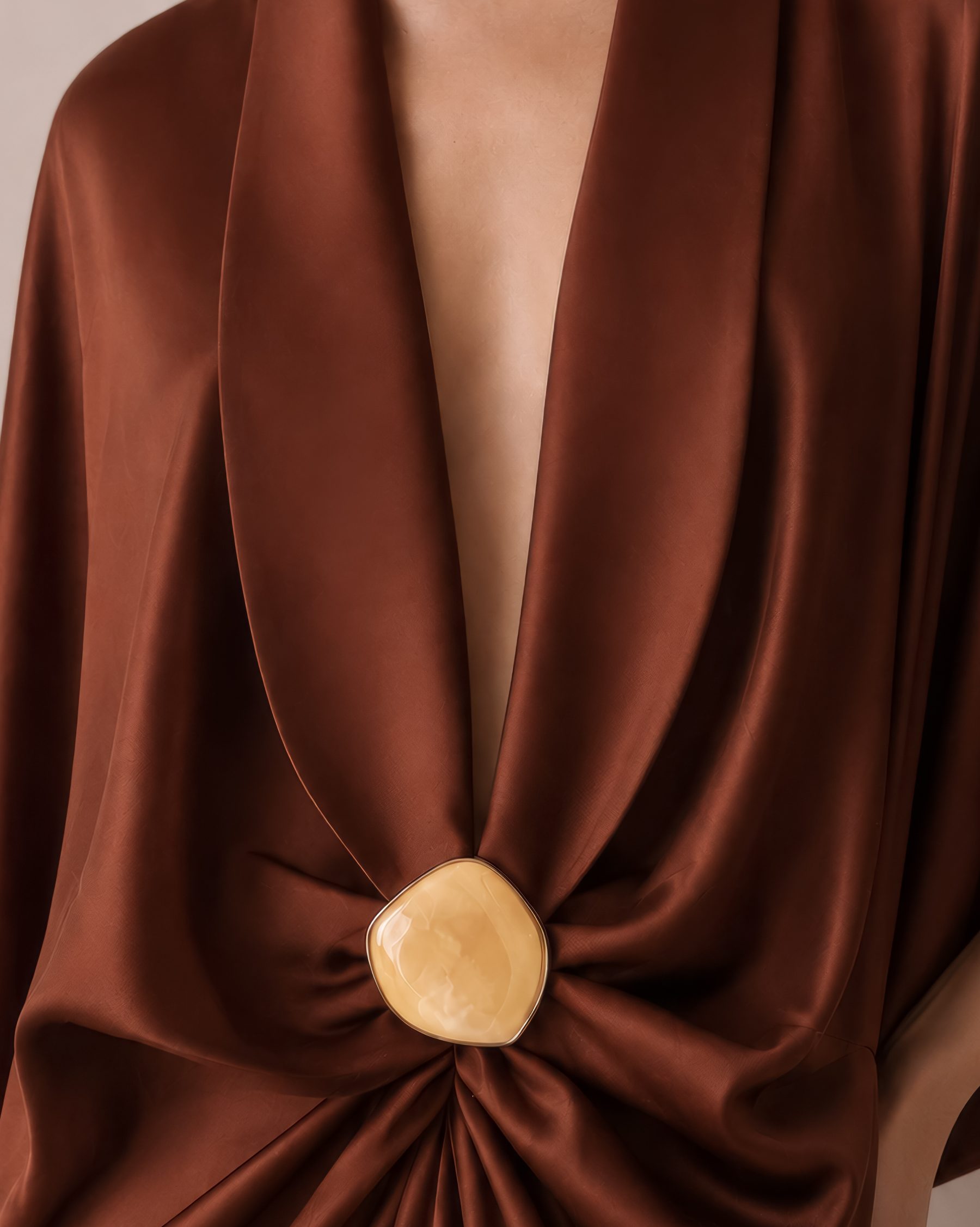 Detail of cognac silk drape with a carved stone